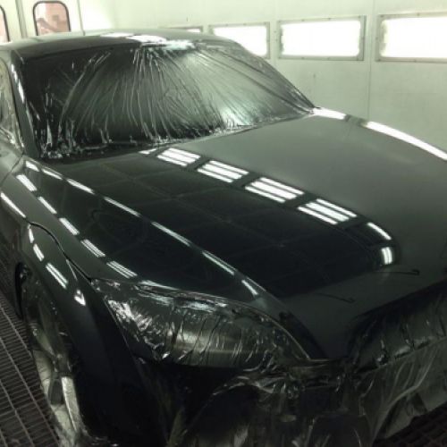 Coche negro dentro de cabina de pintura