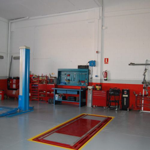 Interior del taller con fachada blanca y zócalo rojo