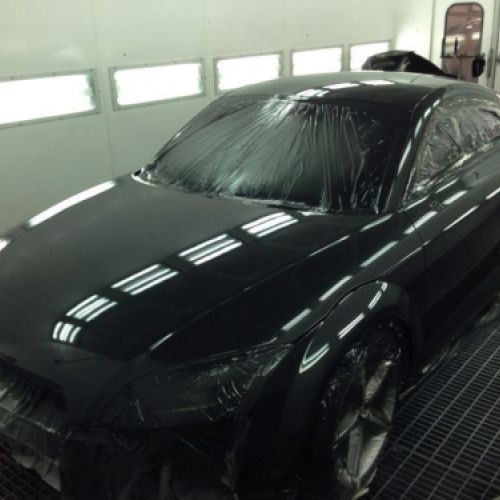 Interior de cabina de pintura con coche negro dentro