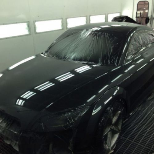 Interior de cabina de pintura con coche negro dentro